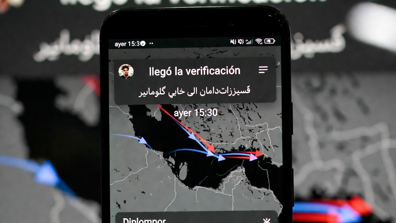 Phone screen showing encrypted diplomatic channel, text in Arabic and Farsi, Hormuz strait map with tanker arrows